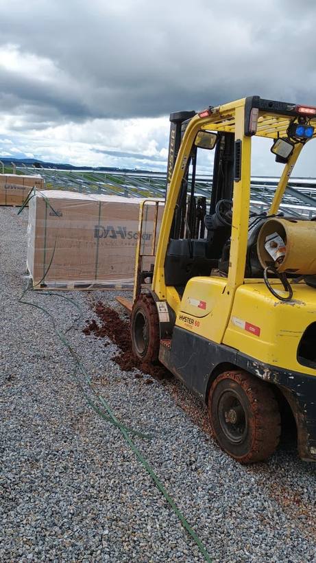 Empilhadeira Fox descarregando paletes de placas solares em obra de usina fotovoltaica