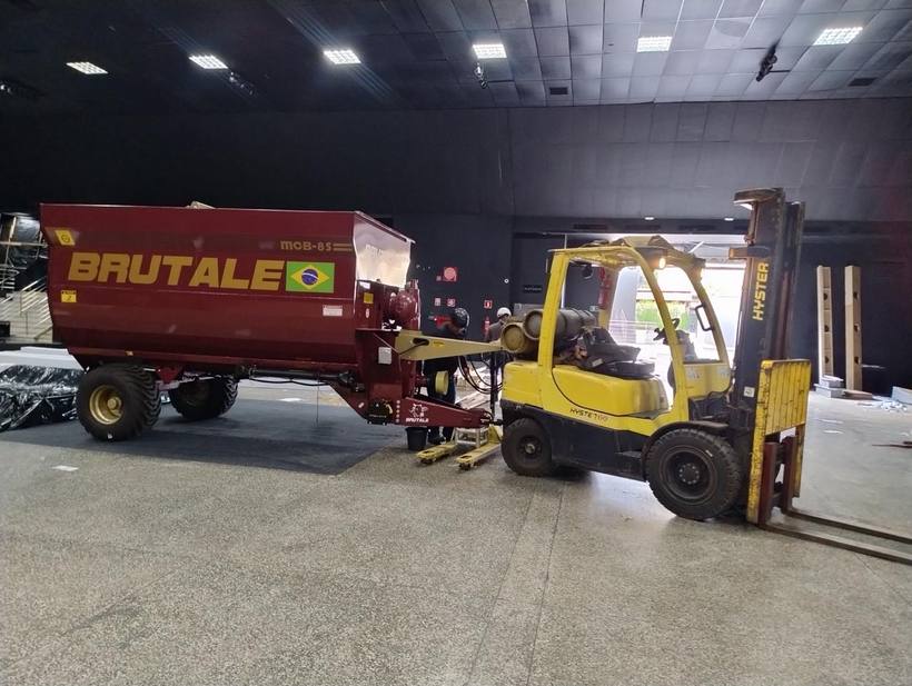Empilhadeira Fox posicionando implemento agrícola em pavilhão de eventos