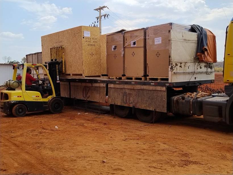 Empilhadeira Fox descarregando engradados de uma carreta em canteiro de obra